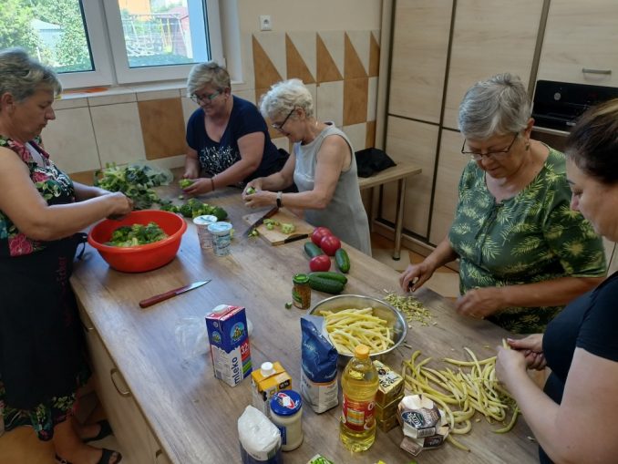 Pięć kobiet przy stole kuchennym przygotowuje potrawy