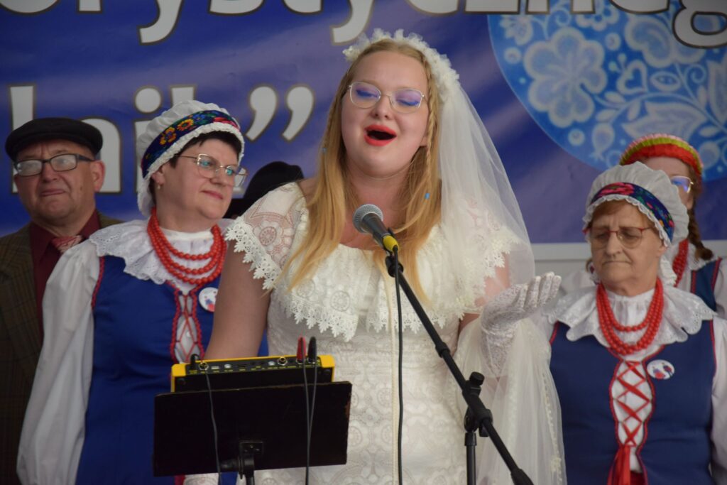Kobieta w białej sukni i welonie śpiewająca piosenkę